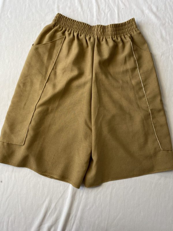 Flat lay of oversized long boxing shorts with elasticated waist and long pockets in beige vintage linen