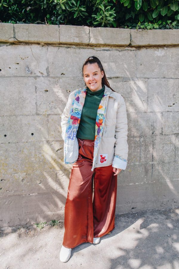 Rosie Sanders wears the beige quilted jacket made from upcycled materials. The lining is a multi colour link print. She also wears the green jersey turtleneck and brown mimosa Trousers. Photograph by Maisie Lee Walker in Bath.